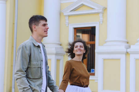 Kharkiv, Ukraine. 09.19.2021. Love story of stylish funny couple: young man in a t-shirt. And a cute young woman in wedding white skirt and yellow sweater. Family holiday and togetherness, dateのeditorial素材