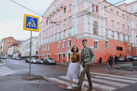 Kharkiv, Ukraine. 09.19.2021. Love story of stylish funny couple: young man in a t-shirt. And a cute young woman in wedding white skirt and yellow sweater. Family holiday and togetherness, dateのeditorial素材