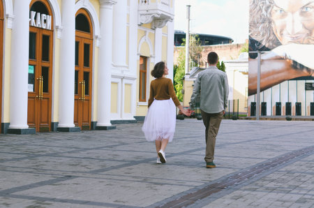 Kharkiv, Ukraine. 09.19.2021. Love story of stylish funny couple: young man in a t-shirt. And a cute young woman in wedding white skirt and yellow sweater. Family holiday and togetherness, dateのeditorial素材