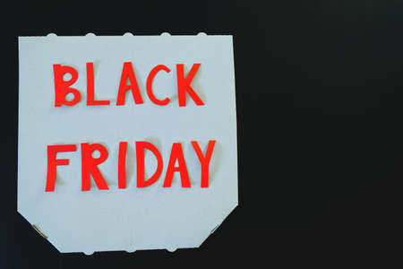 Inscription black friday on a white cardboard pizza box on black background. Copy space, top view,...