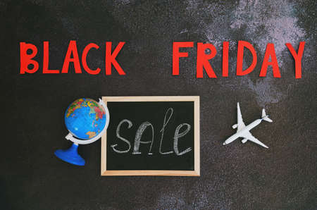 Black Friday concept. Inscription black friday, toy airplane, small globe, writing board with word...