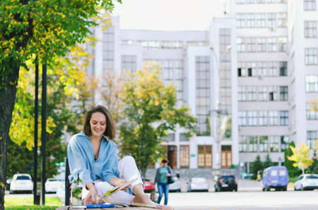 Urban portrait of young elegant business woman in eye glasses and casual clothes. Woman walking in the city street. Drinking healthy smoothie, juice, reading a book and relaxing in day.の写真素材