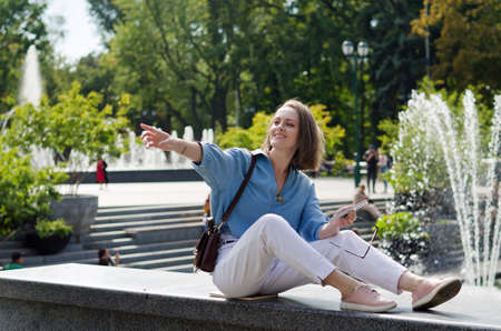 Urban portrait of young elegant business woman in eye glasses and casual clothes. Woman walking in the city street. Drinking healthy smoothie, juice, reading a book and relaxing in day.の写真素材