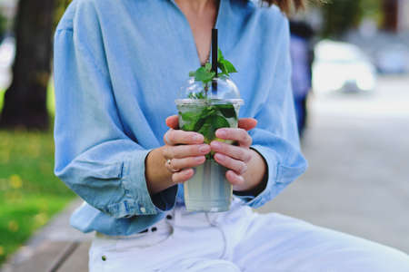 Urban portrait of young elegant business woman in eye glasses and casual clothes. Woman walking in the city street. Drinking healthy smoothie, juice, reading a book and relaxing in day.の写真素材