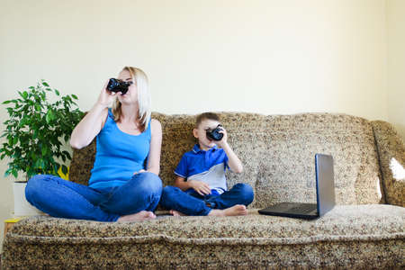 Mother and small child, boy at home sitting on couch, using laptop, relax. Working from home. Happy family lifestyle, hobby and leisure. Business woman conceptの写真素材