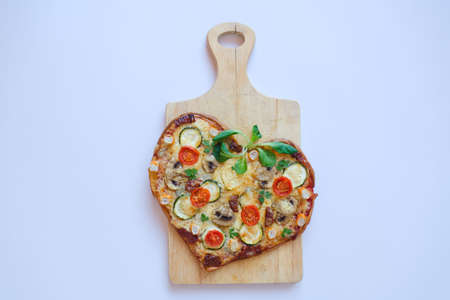 Heart shaped pizza with tomatoes, vegetables and cheese for Valentine's Day on background. Creative food concept of romantic love. Top view, flat lay.の写真素材