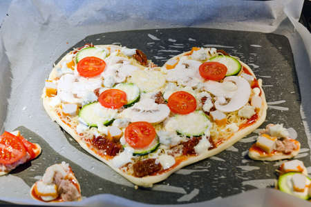Heart shaped pizza with tomatoes, vegetables and cheese for Valentine's Day on background. Creative food concept of romantic love. Top view, flat lay.の写真素材