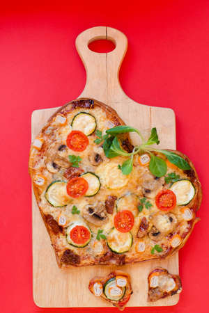 Heart shaped pizza with tomatoes, vegetables and cheese for Valentine's Day on background. Creative food concept of romantic love. Top view, flat lay.の写真素材