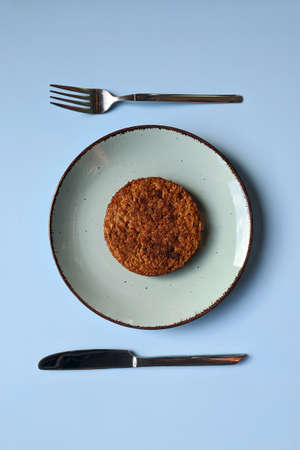 Flat lay of fried veggie burger, cutlet on a blue plate close up. Fork and knife. Dinner. Restaurant...