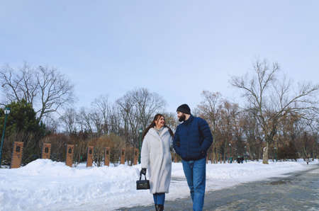 Love story of couple walking in city. Young business man in a blue jacket with a beard. And a cute woman in long coat. talking on the phone, making a selfie. Bloggers. Family holiday, dateの写真素材
