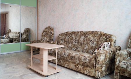 Interior of the room: a coffee table, a sofa, two armchairs and a wardrobe, natural lighting from the windowのeditorial素材