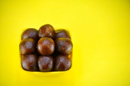Indian dessert gulab jamun served in yellow bowlの写真素材