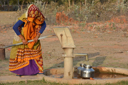 TIKAMGARH, MADHYA PRADESH, INDIA - MARCH 24, 2020: Unidentified Indian woman using hand pump for drinking water.のeditorial素材