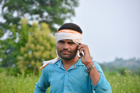 TIKAMGARH, MADHYA PRADESH, INDIA - SEPTEMBER 15, 2020: Indian farmer using mobile phone at sesame field.のeditorial素材