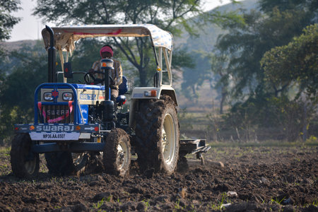 TIKAMGARH, MADHYA PRADESH, INDIA - NOVEMBER 24, 2020: Indian farmer with tractor preparing land for...