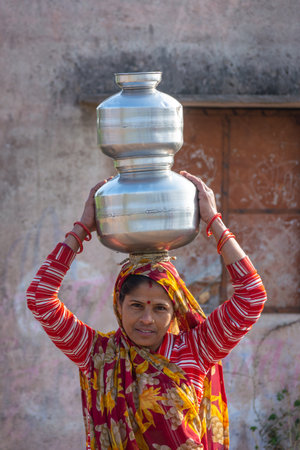 TIKAMGARH, MADHYA PRADESH, INDIA - JANUARY 23, 2021: An Indian woman carrying a container of water on her head.のeditorial素材