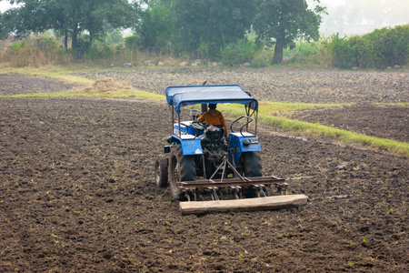 TIKAMGARH, MADHYA PRADESH, INDIA - MAY 02, 2022: Indian farmer working with tractor in agriculture field.のeditorial素材