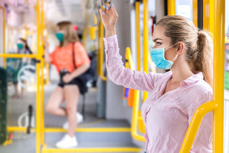 Young woman with respiratory mask traveling in the public transport. Public transport during the coronavirus - concept. Coronavirus, covid 2019の写真素材