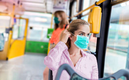 Young woman with respiratory mask traveling in the public transport. Public transport during the coronavirus - concept. Coronavirus, covid 2019の写真素材