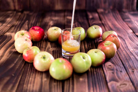 Heart of apples on brown wooden background. Apple juice on wooden table.の写真素材
