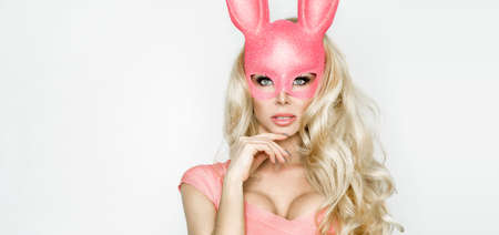 Beautiful sexy, young woman in halloween pink costume and pink mask, standing on white background
