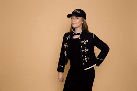 Beautiful blond girl in elegant, autumn clothing on a beige background in the studio.