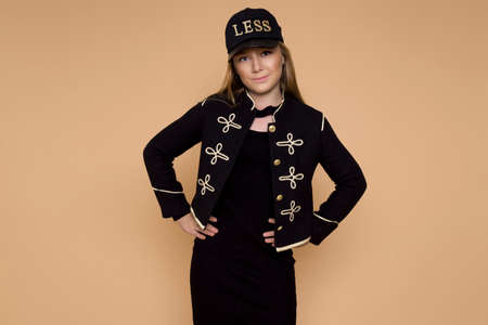Beautiful blond girl in elegant, autumn clothing on a beige background in the studio.
