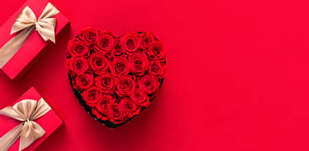 Christmas red background with Christmas gift and flowers decor. Top view with copy space. Minimalism. Merry Christmas.の写真素材