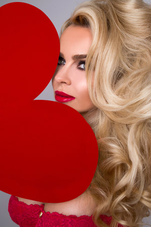 Valentine sexy girl with red heart isolated on white background. Beautiful Happy Young woman portrait. Holiday party, birthday. Valentine's day- concept.の写真素材