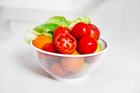 Fresh salad with raw vegetables and herbs. Basket with fresh fruits and vegetables isolated on white...