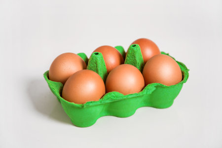 Close-up view of raw chicken eggs in egg box on white wooden backgroundの写真素材