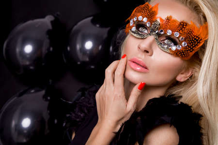 Beautiful Blond Woman in a Carnival Mask on balloons background. Masquerade. Sexy Girl in mask. Beauty and Fashionの写真素材