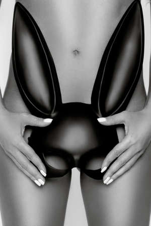 Sexy naked model is covered with a black rabbit mask. Black and white photo.の写真素材