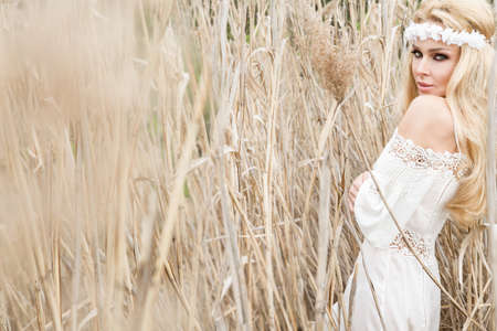 Beauty Girl Outdoors enjoying nature. Beautiful Model girl in white dress running on the Spring Field, Sun Light.の写真素材