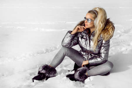Young woman winter portrait. Winter fashion model with ski suit and goggles. Attractive young woman in wintertime outdoor. Mountains, white snow in magic winter day.の写真素材