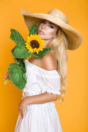 Spring fashion. Beautiful elegant woman in elegance yellow clothing and hat posing in studio on yellow pastel background. Natural beauty concept.の写真素材
