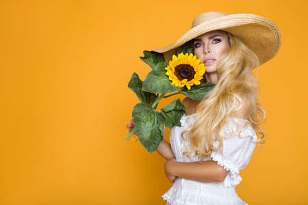 Spring fashion. Beautiful elegant woman in elegance yellow clothing and hat posing in studio on yellow pastel background. Natural beauty concept.の写真素材
