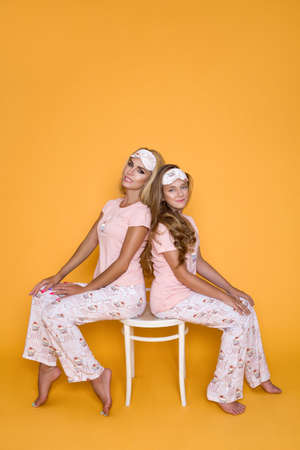 Family in pajamas. Happy family, mother and daughter in similar pajamas on yellow, pastel background. Pajamas fashion. Sleepwear.の写真素材
