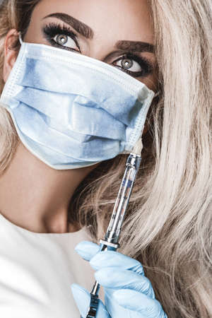 Coronavirus vaccine. Nurse with medical mask holds a covid-19 vaccine. Stop the virus! Vaccine concept.の写真素材