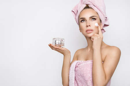 Beautiful blonde woman holding a face cream. Beautiful young woman with clean fresh skin. Facial treatment. Cosmetology, beauty and spa. Skin care - Image. Wellness.の写真素材