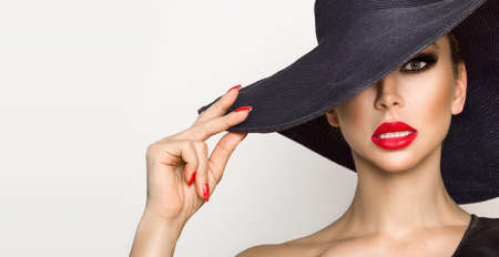 Portrait of elegant woman in a hat and with red lips on a white background in studio. Elegance. Hat...
