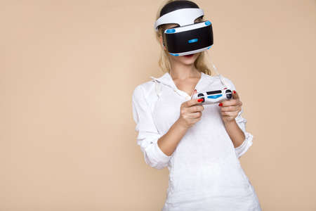 Beautiful woman touching air during the VR experience isolated on beige, pastel background. Woman...