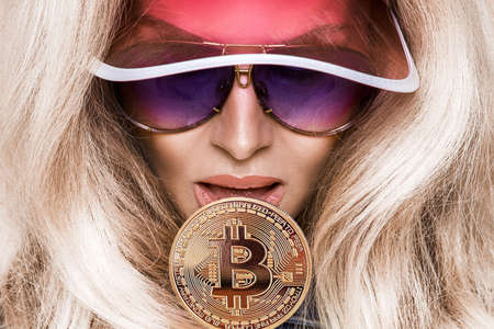 Beautiful blonde girl with bitcoin lollipop and sunglasses. Bitcoin cryptocurrency. Sexy woman with bitcoin.の写真素材
