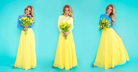 Spring fashion Woman. Beautiful happy woman with colorful dress, holding a bouquet of spring flowers on blue background in studio. Fashion photo. Spring flowers - concept. Woman with Easter tulips.の写真素材