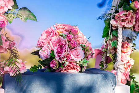 Wedding bouquet of pink, pastel roses outdoors on the swing decorated with fresh flowers. Spring flowers. Bridal. Wedding outdoor.の写真素材