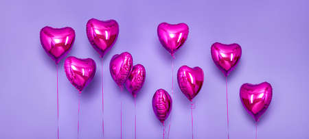 Set of Air Balloons. Bunch of pink color heart shaped foil balloons isolated on purple background. Love. Holiday celebrates. Valentine's Day party decoration. Metallic red Heart air balloonsの写真素材