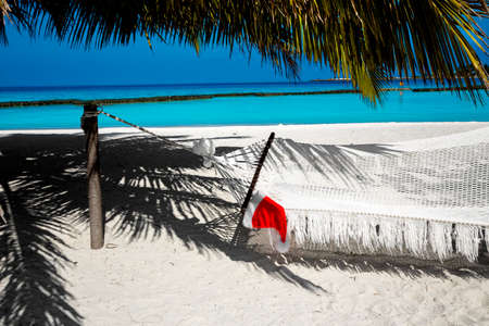 Santa Claus hat at caribbean sandy beach, Maldives. Santa Clause hat on hammock on the beach. Holiday concept - Imageの写真素材