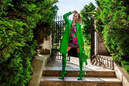 Spring, summer fashion. High fashion model. Glamor, stylish elegant woman. Female model in colorful dress and Trendy green coat in the city. Outdoor shoot. Casual, urban style. Vogue.の写真素材