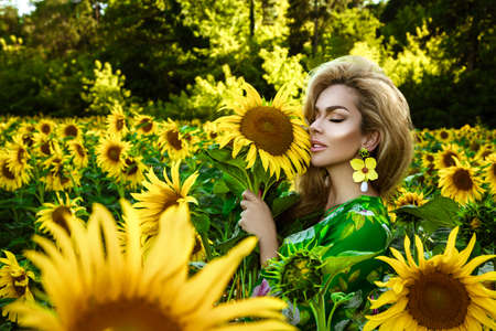 Beautiful young woman in a field of sunflowers. Happy female model is holding sunflower in Sunflowers field. Natural beauty.の写真素材