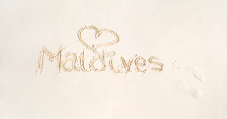 Inscription Maldives on sand beach. Maldives sandy beach with an inscription on the sand. Vacation concept - Image. Luxury travel.の写真素材
